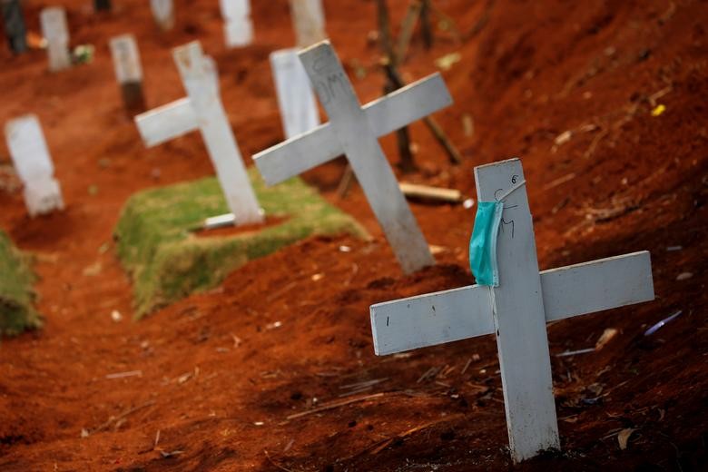 A protective mask hangs on a cross at the burial area provided by the government for victims of the coronavirus at Pondok Ranggon cemetery complex, as the outbreak continues in Jakarta, Indonesia. REUTERS/Willy Kurniawan  